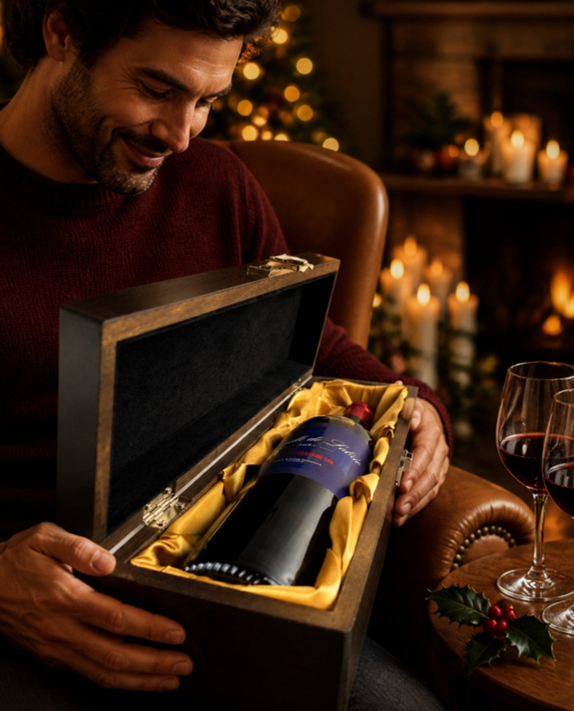Man in an armchair on a candlelit Christmas evening opening the Chapelle de Labrie Saint-Émilion Grand Cru 2021 in its elm wood gift box